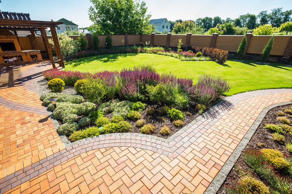 there is a brick walkway in the middle of the garden .
