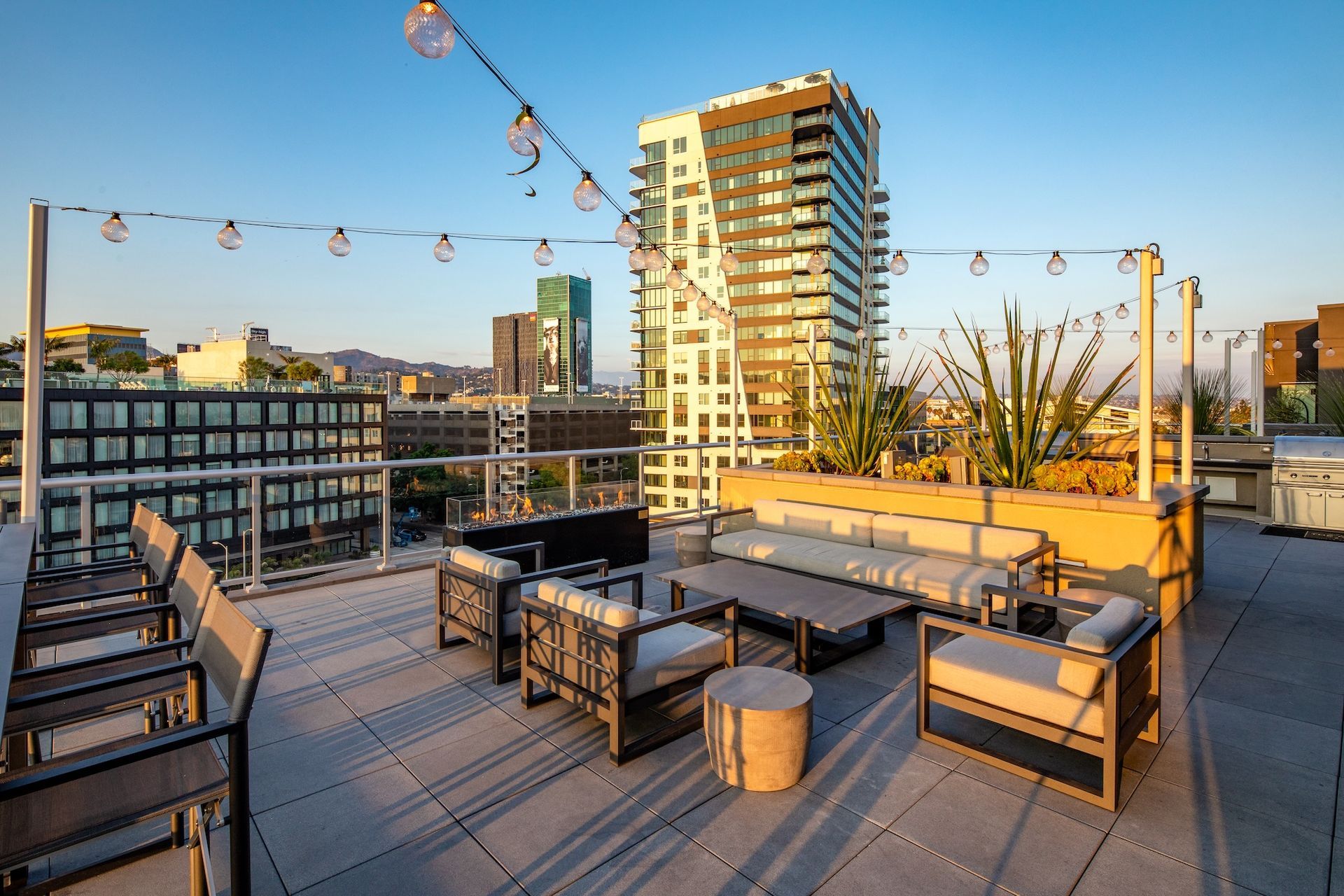 Rooftop patio with seating, string lights, and city views.