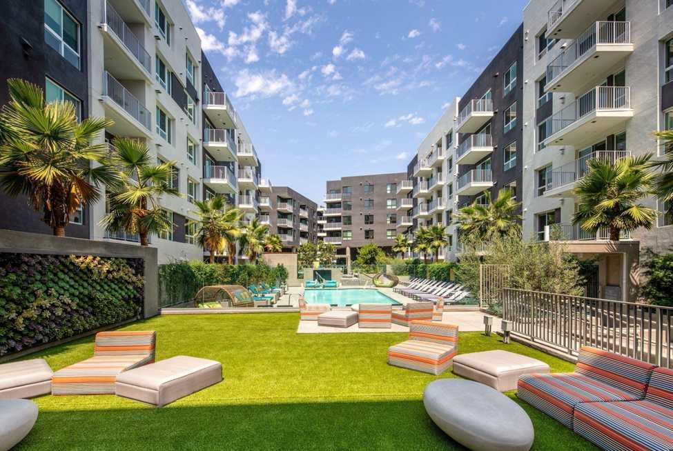A rooftop terrace with planters, bistro tables, string lights, and skyline views at The Ovelo Hollywood.