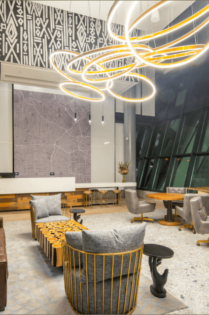 Lounge area with modern decor, circular lights, stone wall, unique seating, and a large window.