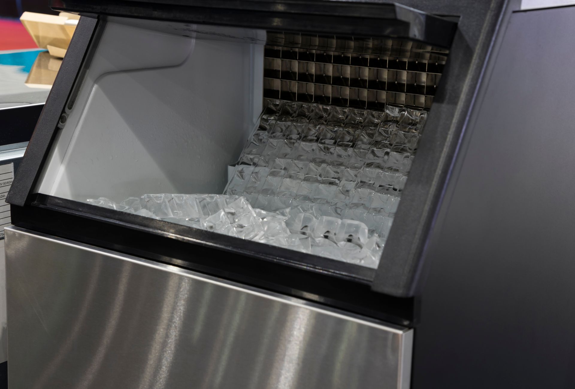 Open commercial ice machine bin filled with clear ice cubes, showing the interior storage area.