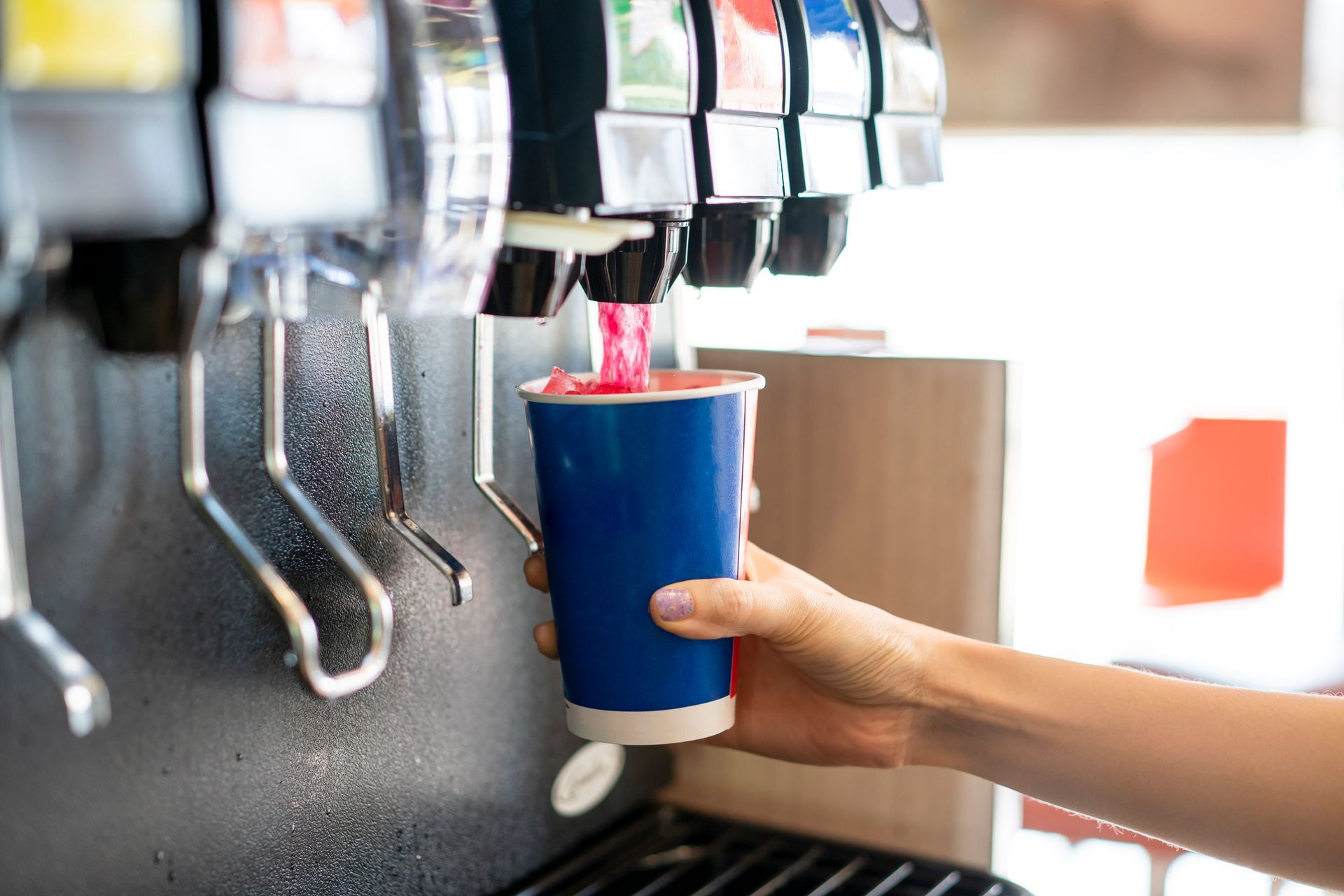 A man pours a fizzy red drink from a soda fountain.
