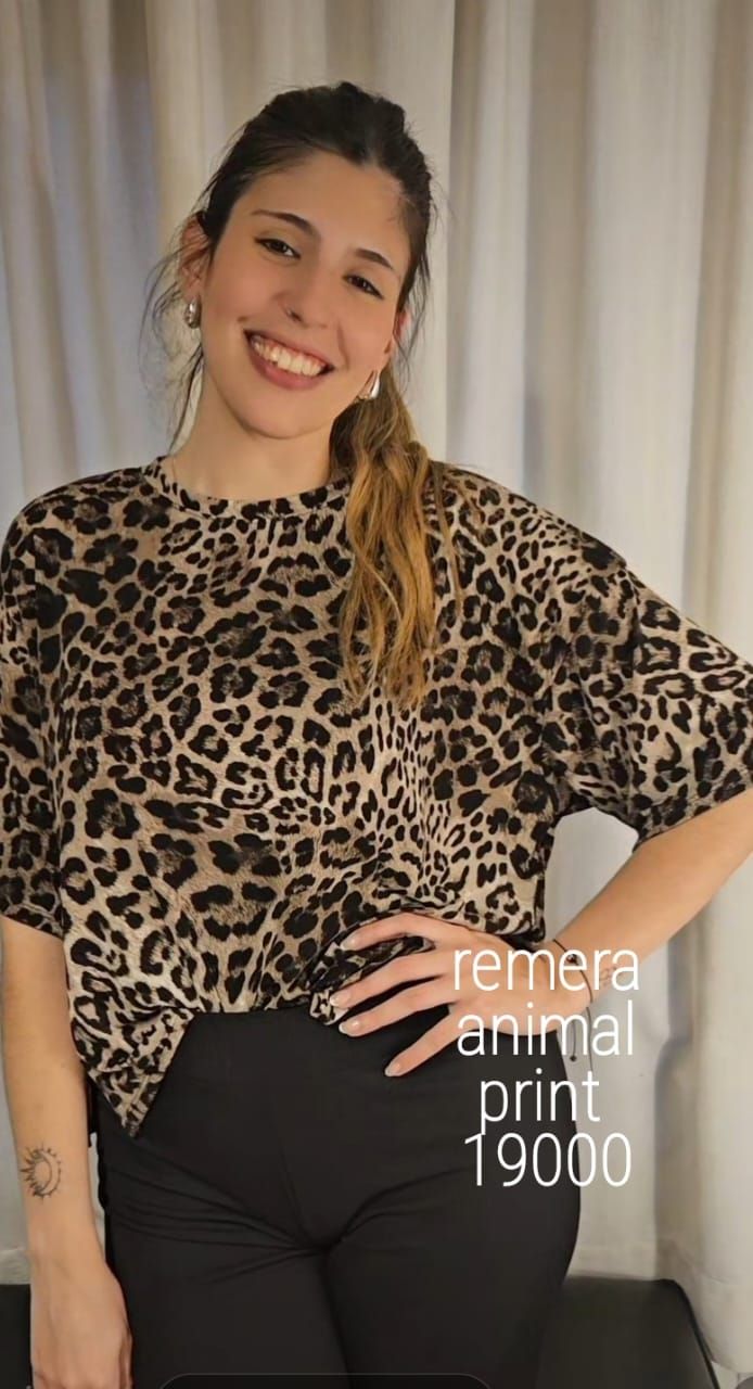 Mujer con camisa de estampado animal, sonriente, posa en interiores. El texto dice 