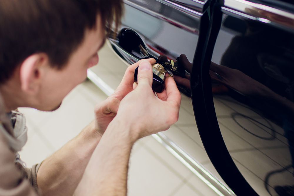 Person Using a Tool to Open a Black Car Door Lock — Terrace Locksmiths in Raymond Terrace, NSW
