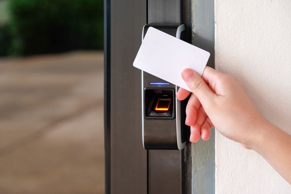 Hand holding a white card at a door access card reader with a lit scanner — Terrace Locksmiths in Raymond Terrace, NSW