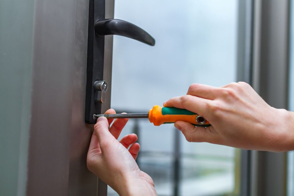 Hands using a screwdriver to adjust a door handle lock. — Terrace Locksmiths in Raymond Terrace, NSW