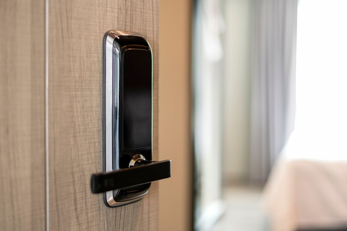 A Black Door Handle on a Wooden Door With a Blurred Hallway — Terrace Locksmiths in Raymond Terrace, NSW