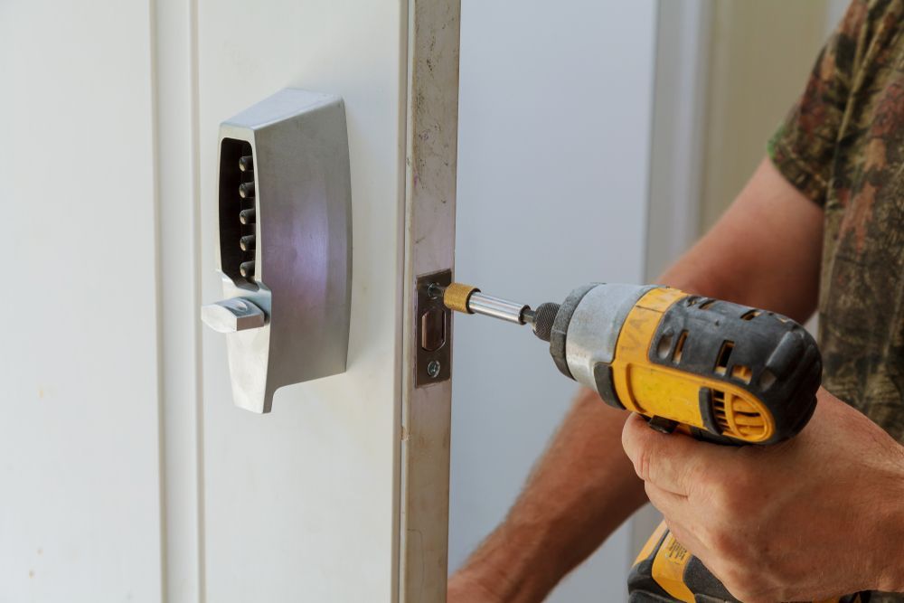 Person Using a Drill to Install a Silver Smart Lock on A White Door — Terrace Locksmiths in Warners Bay, NSW