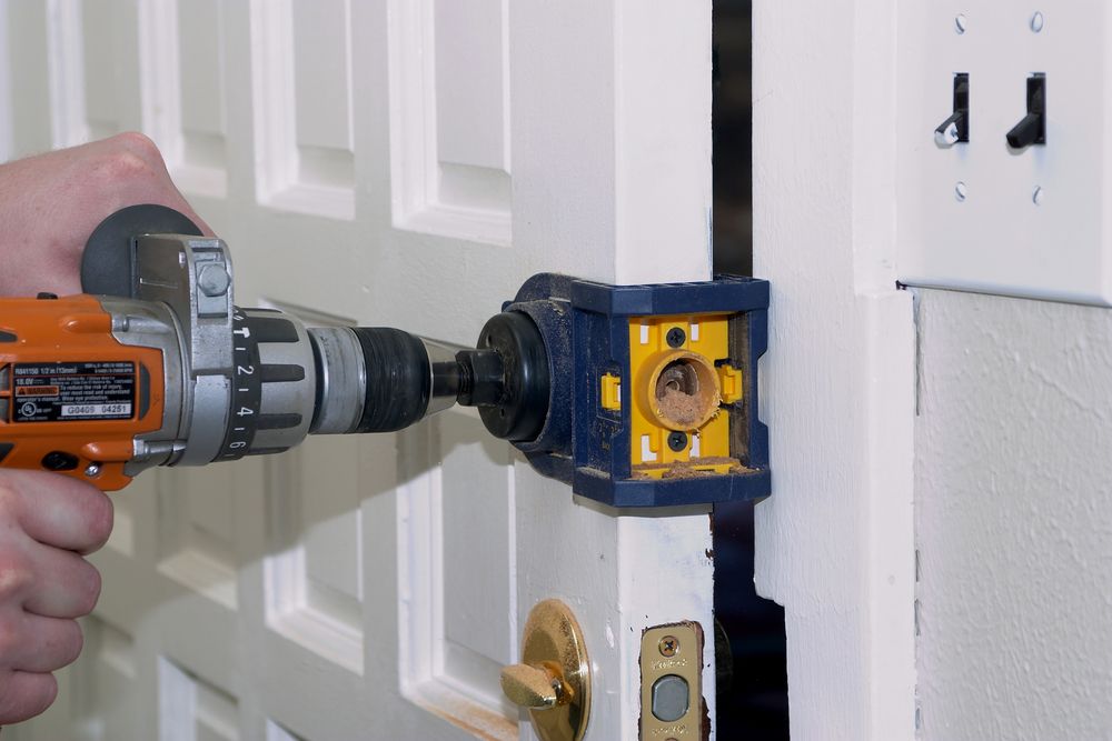 Drill Installing a Metal Door Latch Into a White Door Frame with A Blue Jig — Terrace Locksmiths in Raymond Terrace, NSW