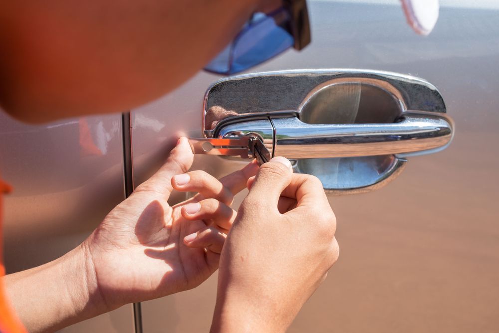 Hands Unlocking a Silver Car Door with A Key Near the Handle — Terrace Locksmiths in Nelson Bay, NSW