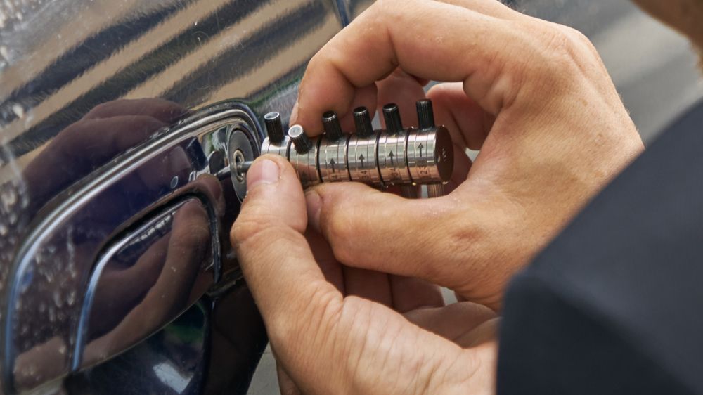 Hands Fitting a Combination Lock to The Temple of Black Eyeglasses — Terrace Locksmiths in Port Stephens, NSW
