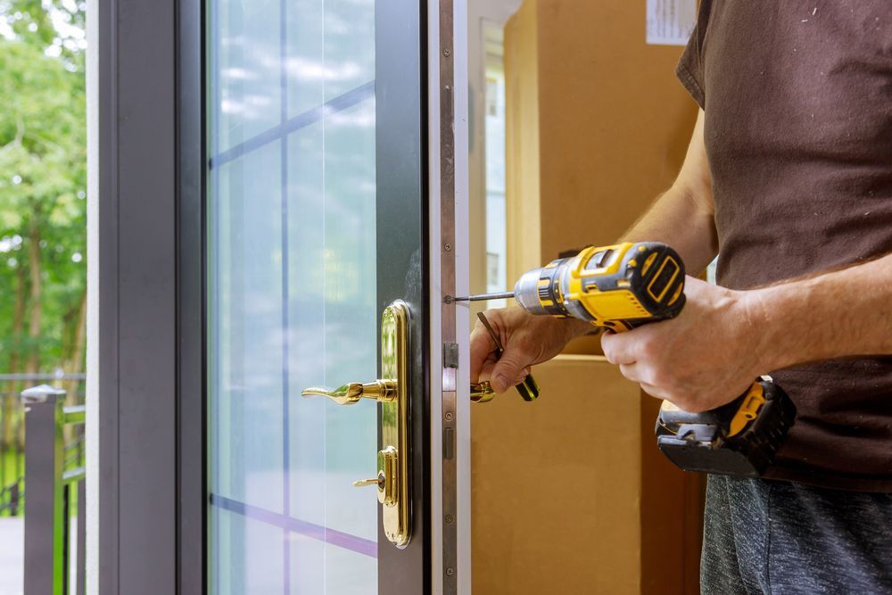 Person Using a Cordless Drill to Install a Door Lock on A Glass Front Door — Terrace Locksmiths in Raymond Terrace, NSW