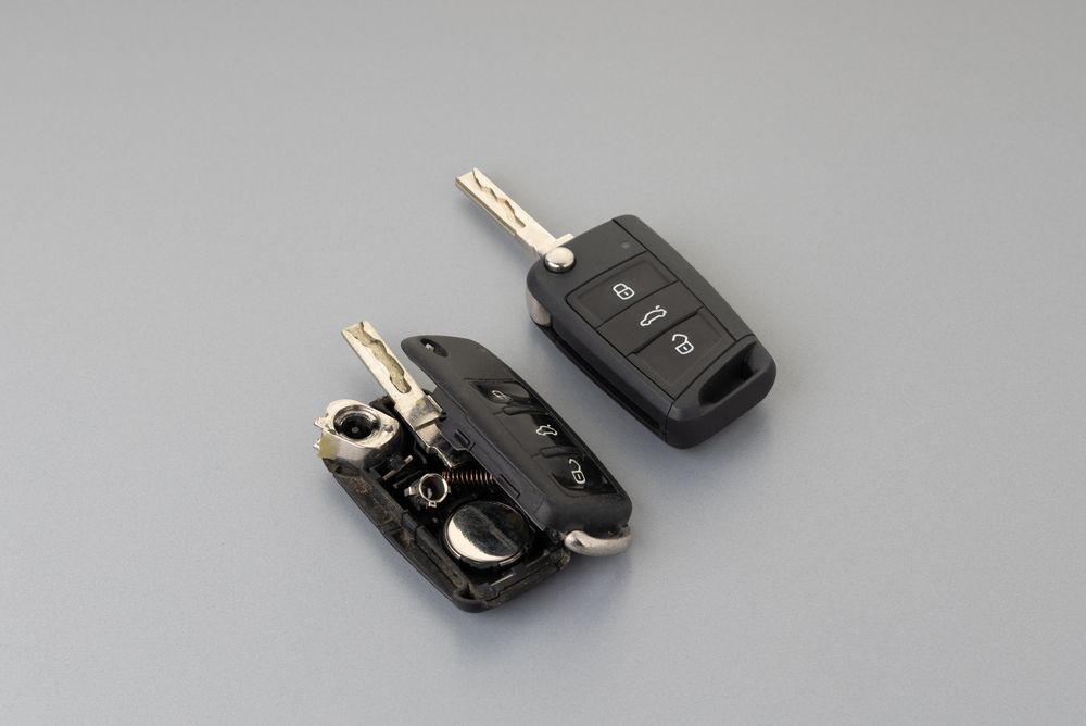 Two Black Car Key Fobs and A Bare Key on A Gray Surface — Terrace Locksmiths in Raymond Terrace, NSW