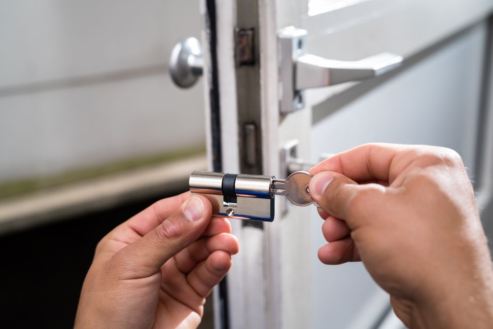 Hands unlocking a silver door lock with a key — Terrace Locksmiths in Raymond Terrace, NSW