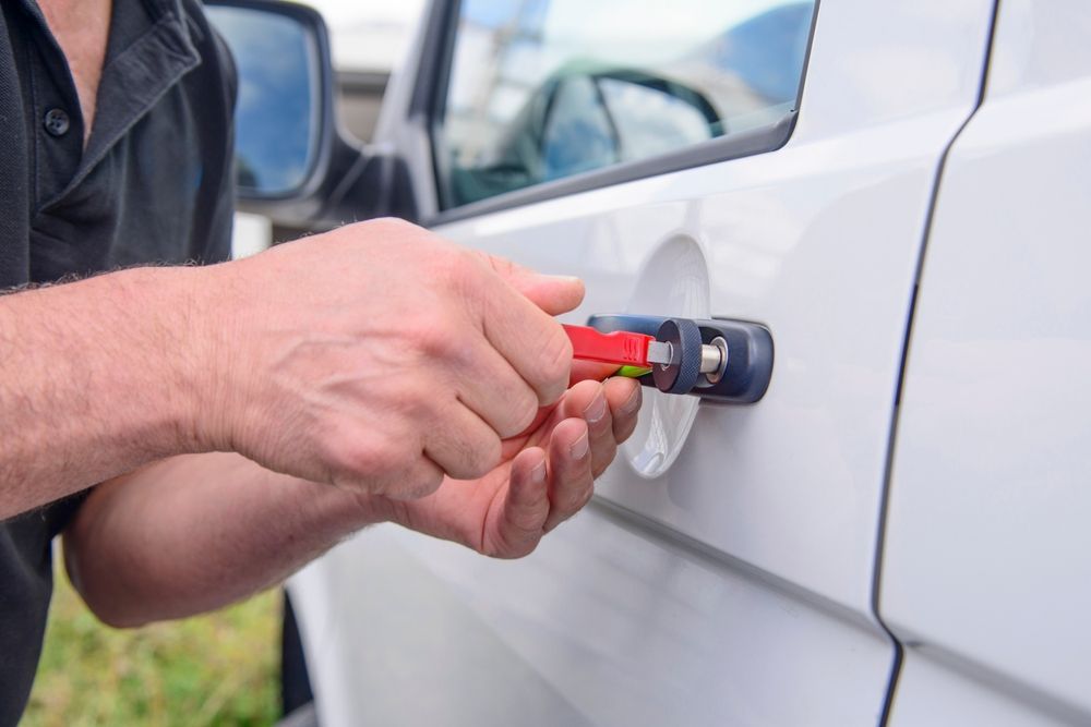 Hand using a tool to remove a white car door lock — Terrace Locksmiths in Raymond Terrace, NSW