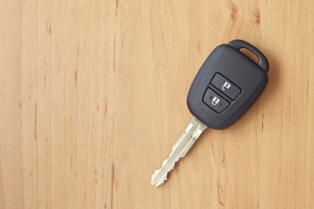 Black Car Key with Remote Buttons on A Wooden Surface — Terrace Locksmiths in Raymond Terrace, NSW