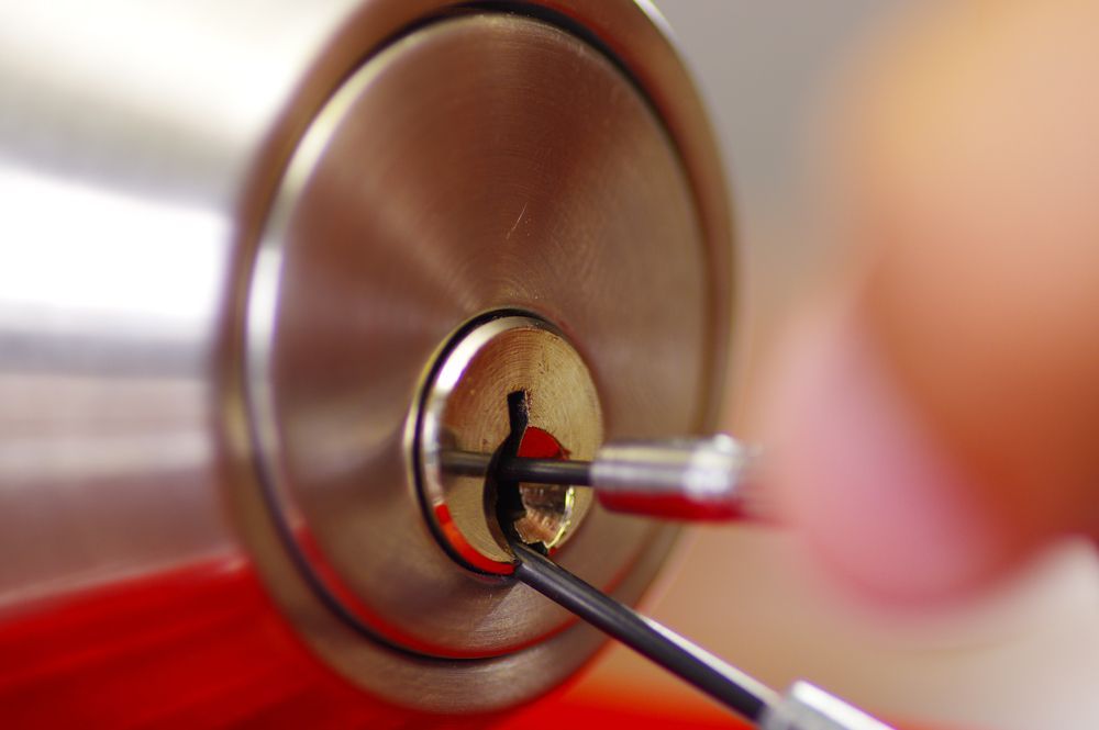 Lock Being Picked With a Red-handled Tool and Tension Wrench — Terrace Locksmiths in Raymond Terrace, NSW