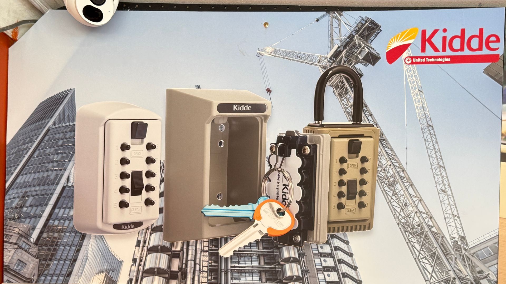 Kidde fire alarm ad with three control panels and a city skyline under construction in the background — Terrace Locksmiths in Raymond Terrace, NSW