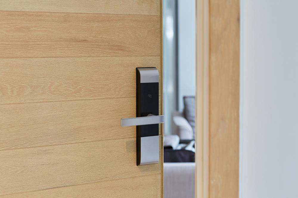 A Wooden Door With a Black Handle and a Sliver of Room Visible — Terrace Locksmiths in Raymond Terrace, NSW