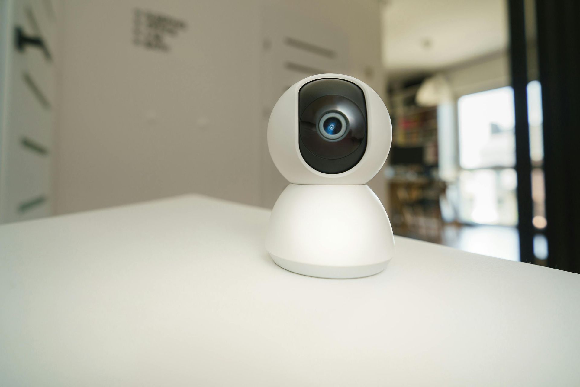 White Indoor Security Camera on A Table, with A Blurred Room in The Background — Terrace Locksmiths in Raymond Terrace, NSW
