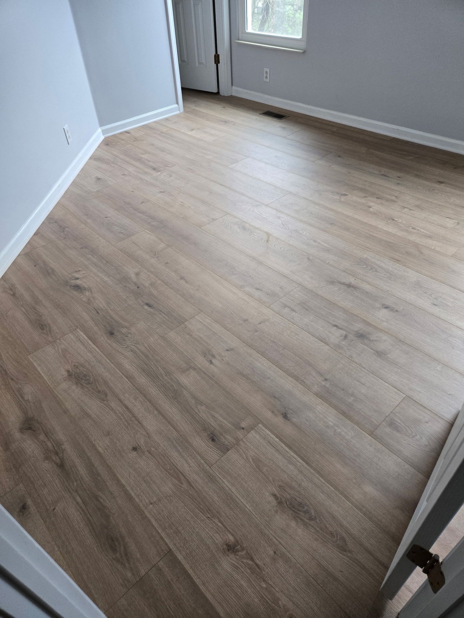 A bedroom with a wooden floor and a window.