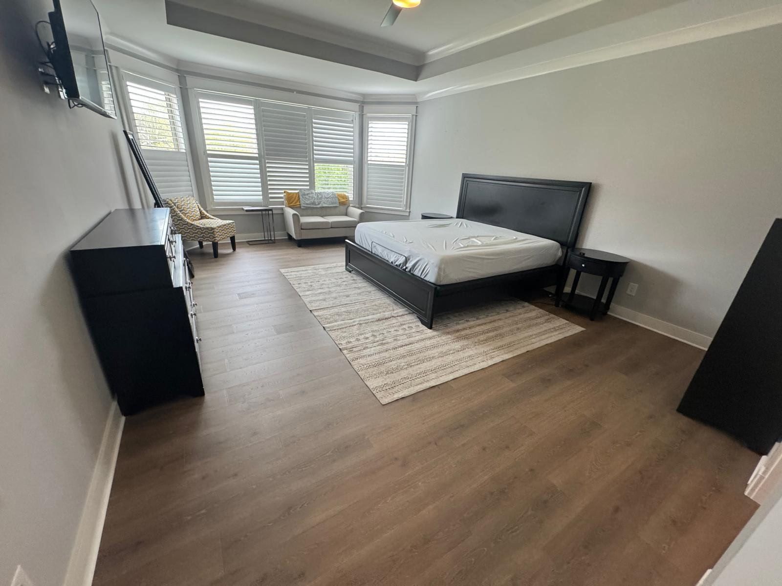 A bedroom with a bed , dresser , chair and television.