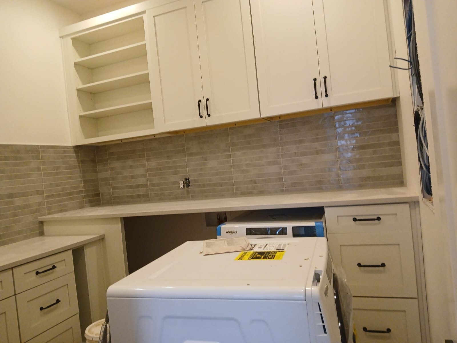 A laundry room with a washer and dryer and white cabinets.