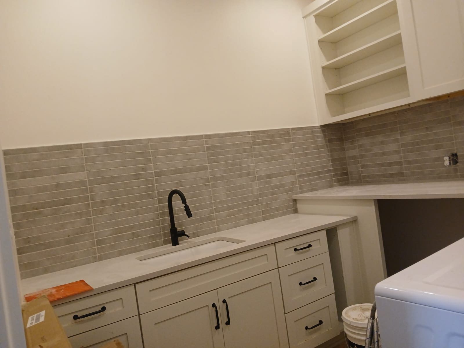 A laundry room with white cabinets , a sink , and a washer and dryer.
