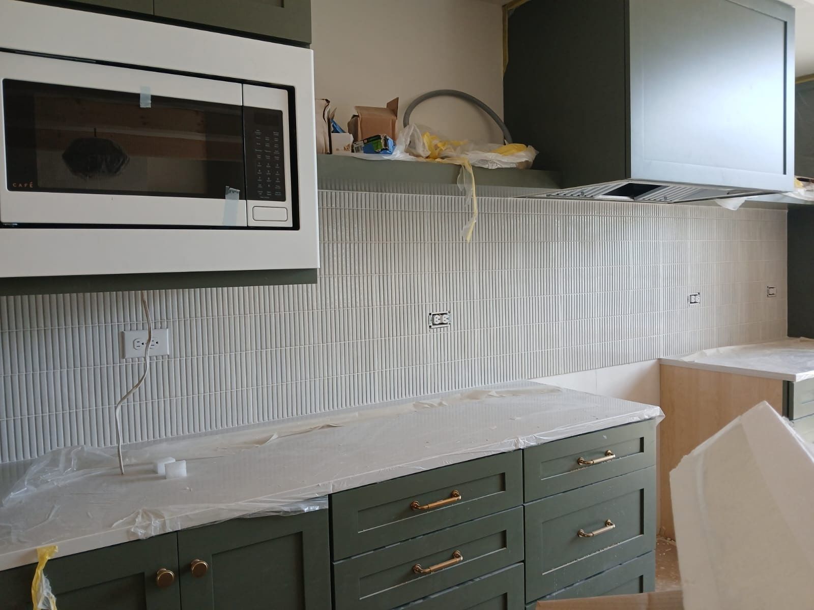 A kitchen with green cabinets and a white microwave.