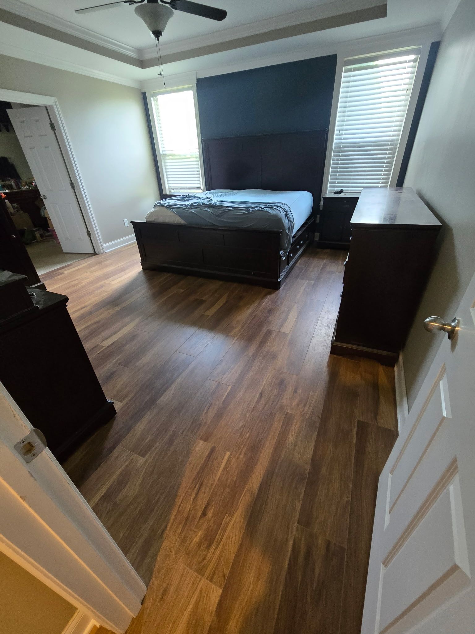 Bedroom with dark wood furniture, bed, and dresser, hardwood floor, and closed windows with blinds.