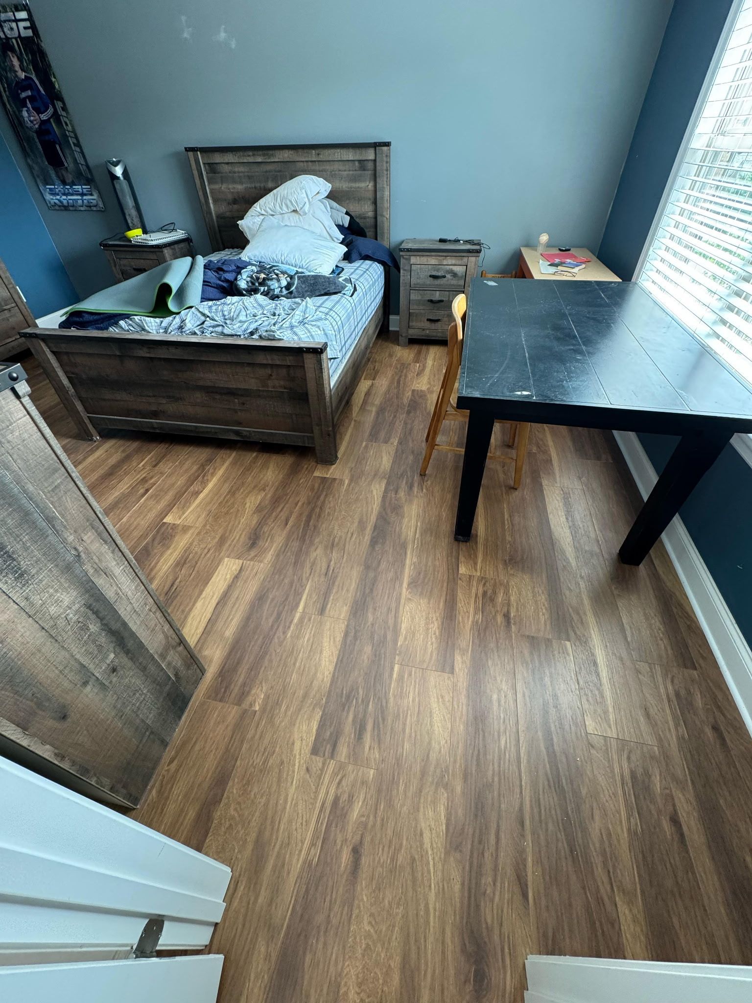 Bedroom with a bed, nightstand, desk, and wood-look flooring.