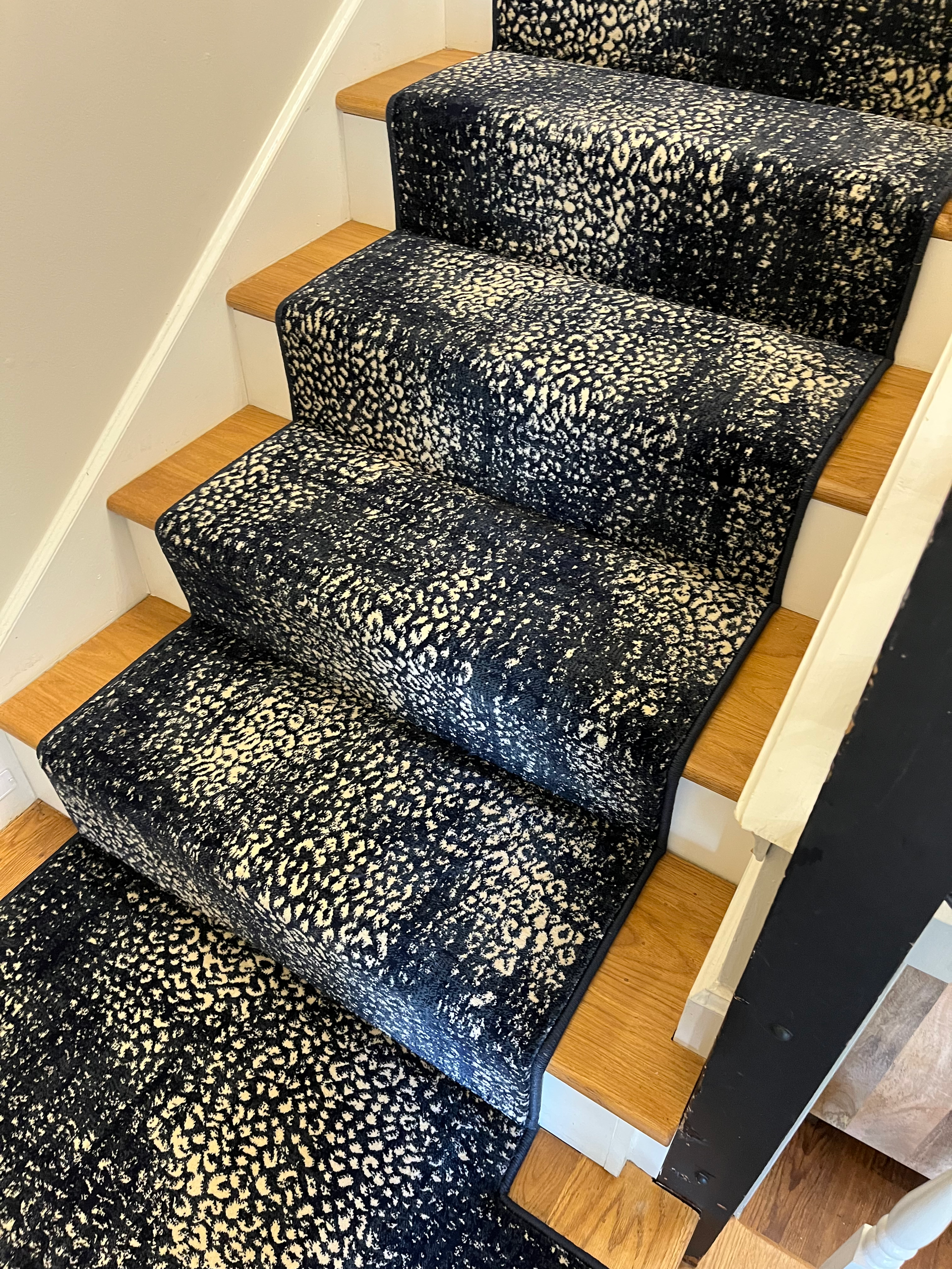 Carpeted staircase with navy blue and white speckled pattern, wooden steps.