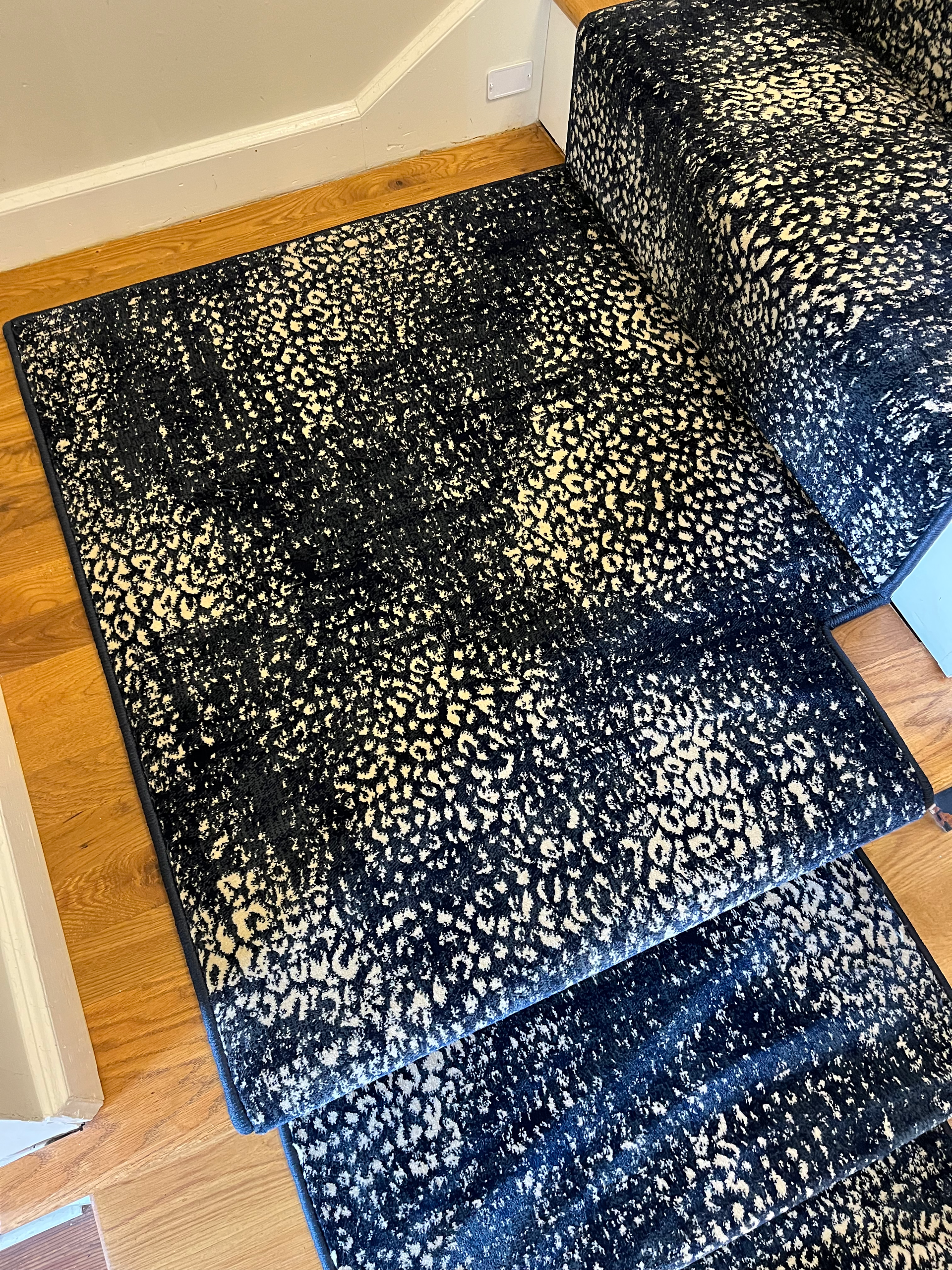 Navy and white patterned rug on a wooden staircase.