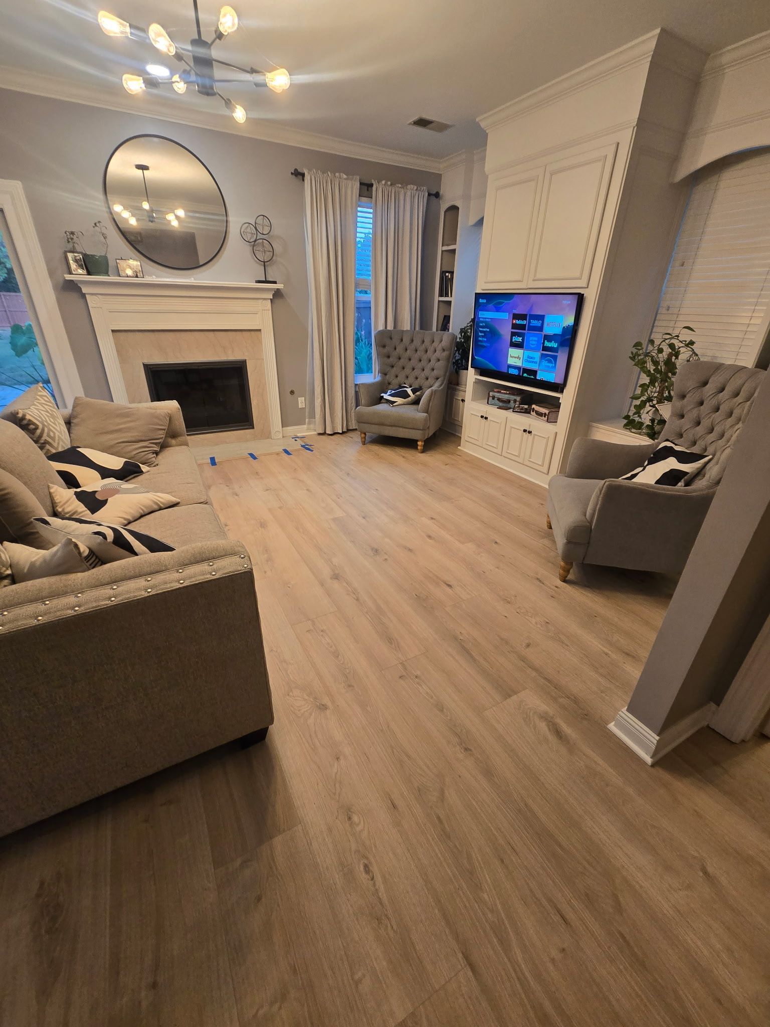 Living room with fireplace, gray walls, light wood floor, and gray armchairs.