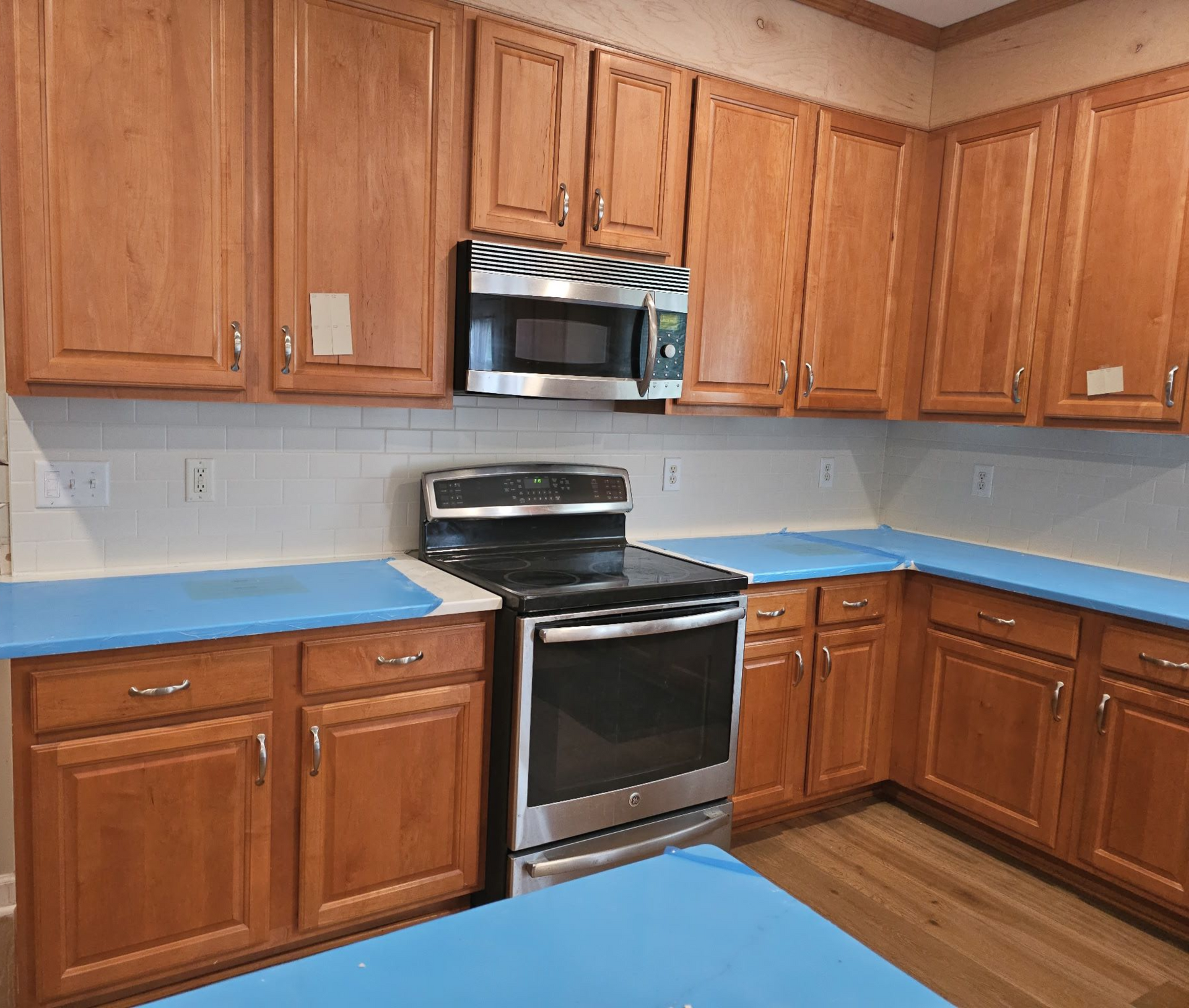 Kitchen with wooden cabinets, stainless steel appliances, and blue counter protection.