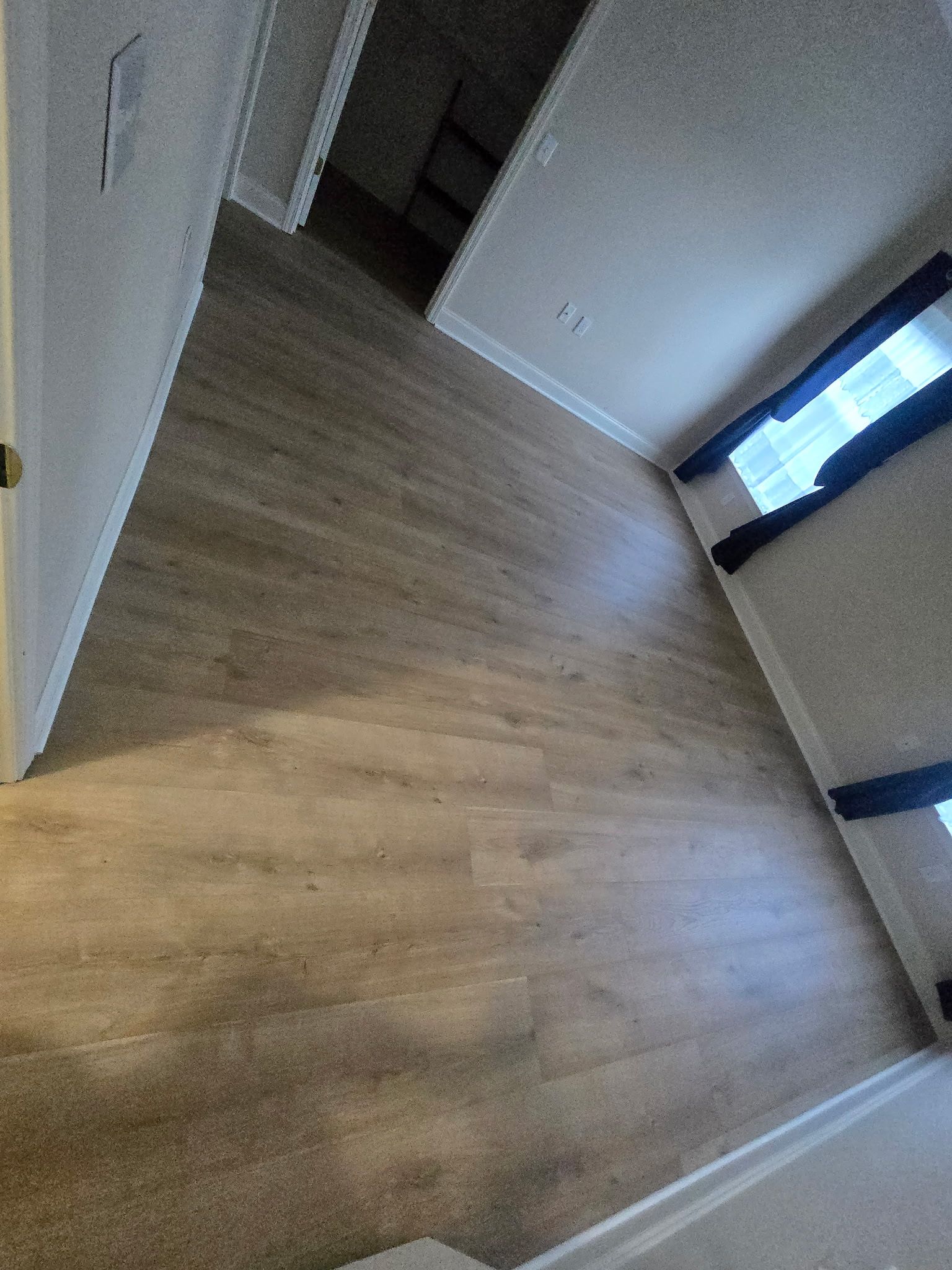 Wood-look flooring in a room with a window and white trim.