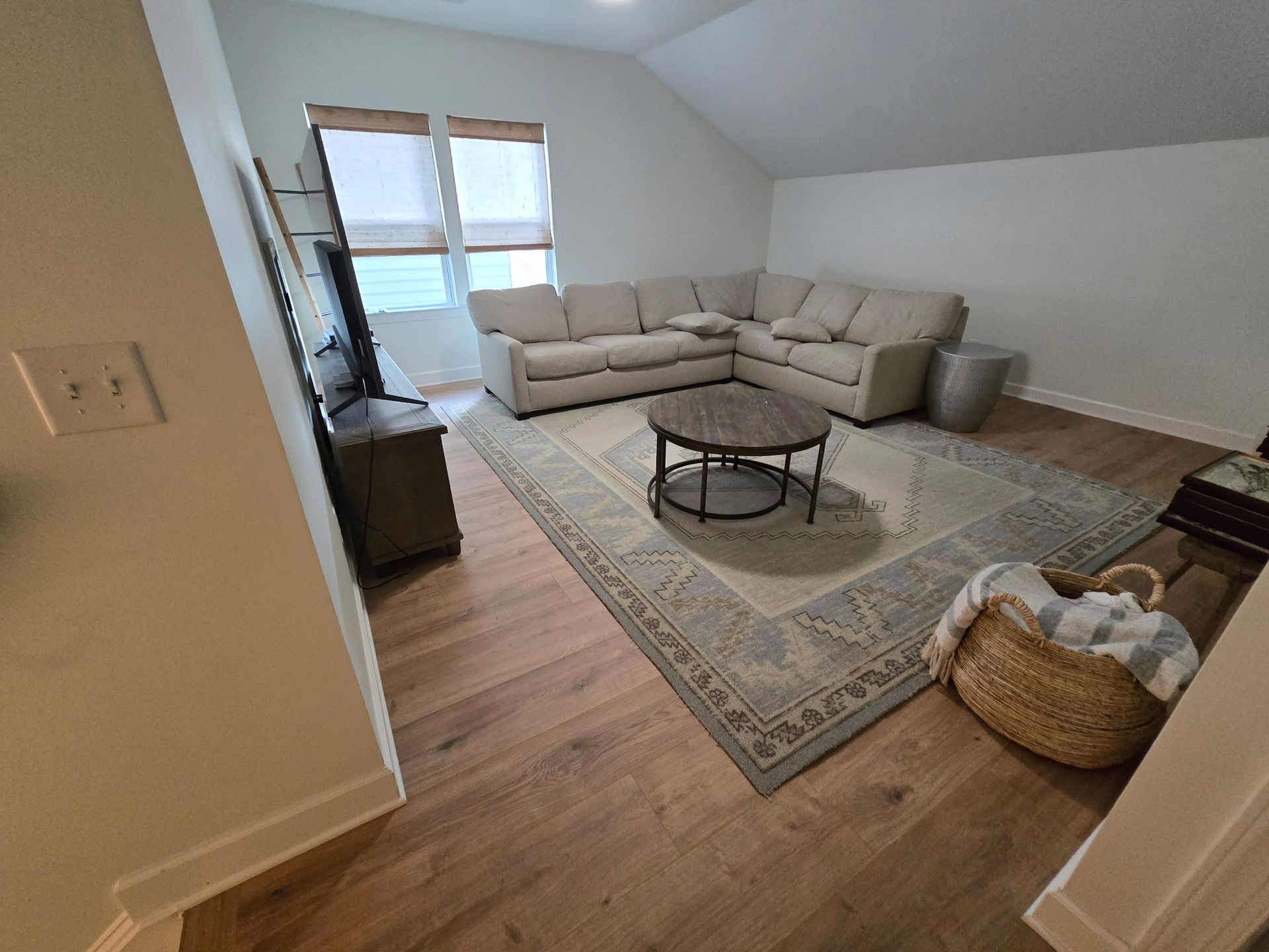 Living room with sectional sofa, rug, coffee table, TV, and large window.