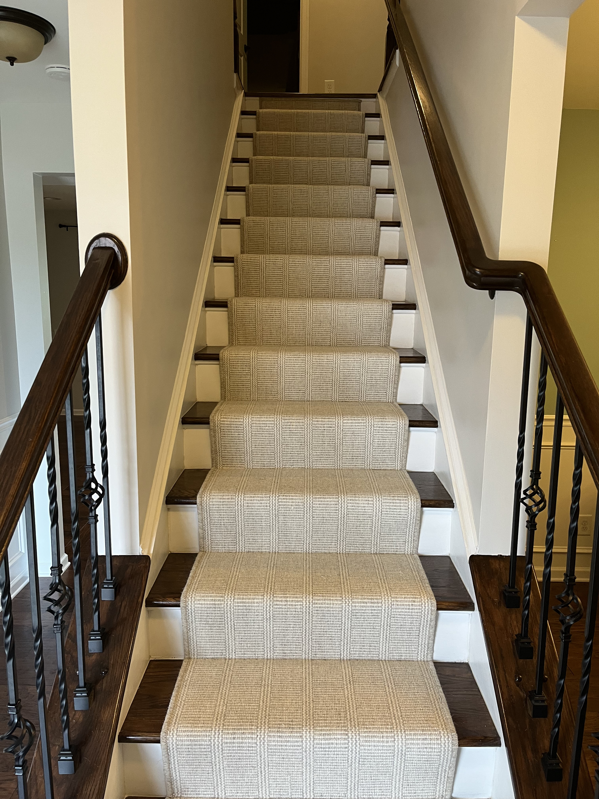 Carpeted staircase with dark wooden banisters in a beige hallway