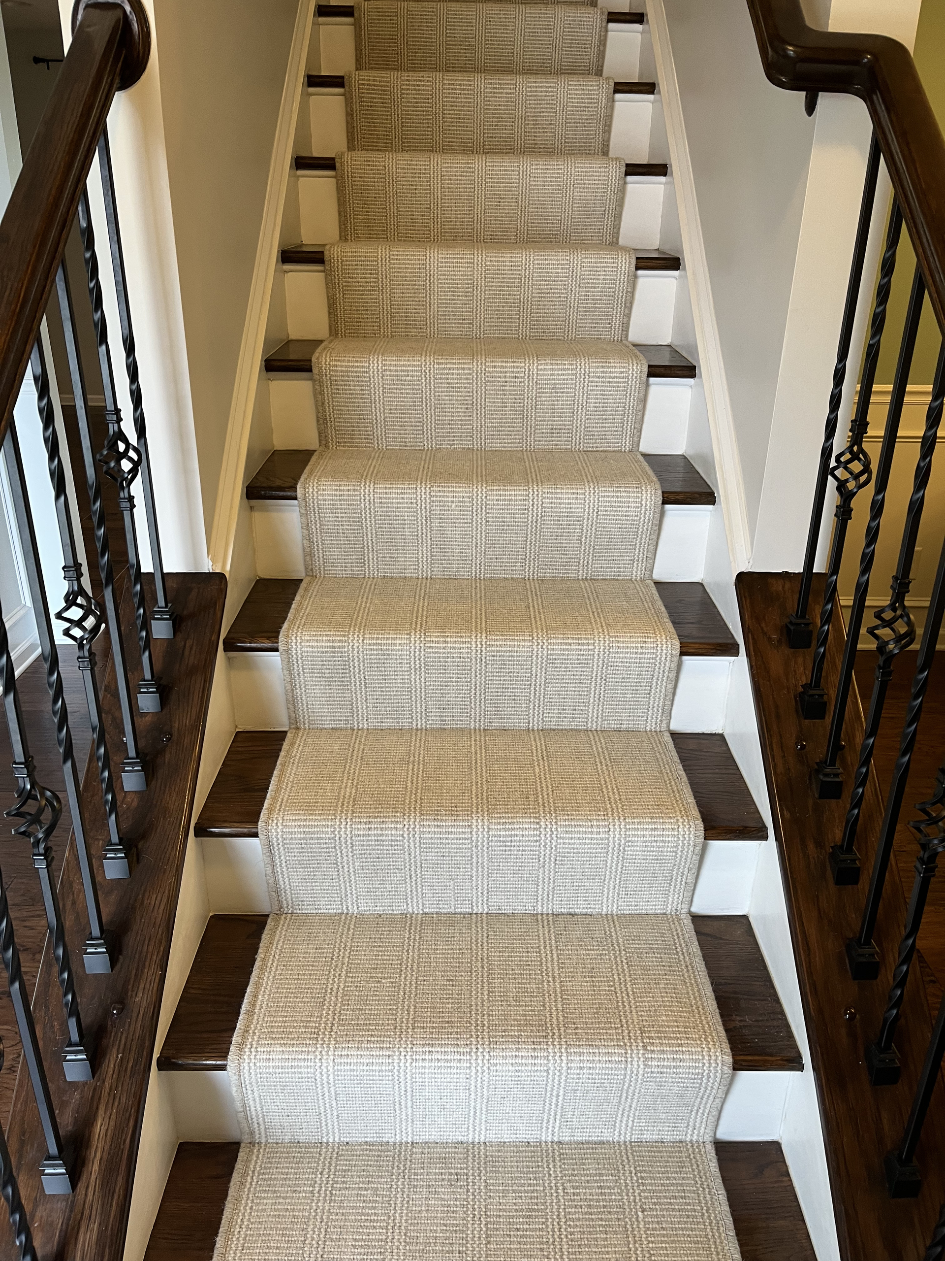 Carpeted staircase with patterned runner and black metal railings in a home interior.