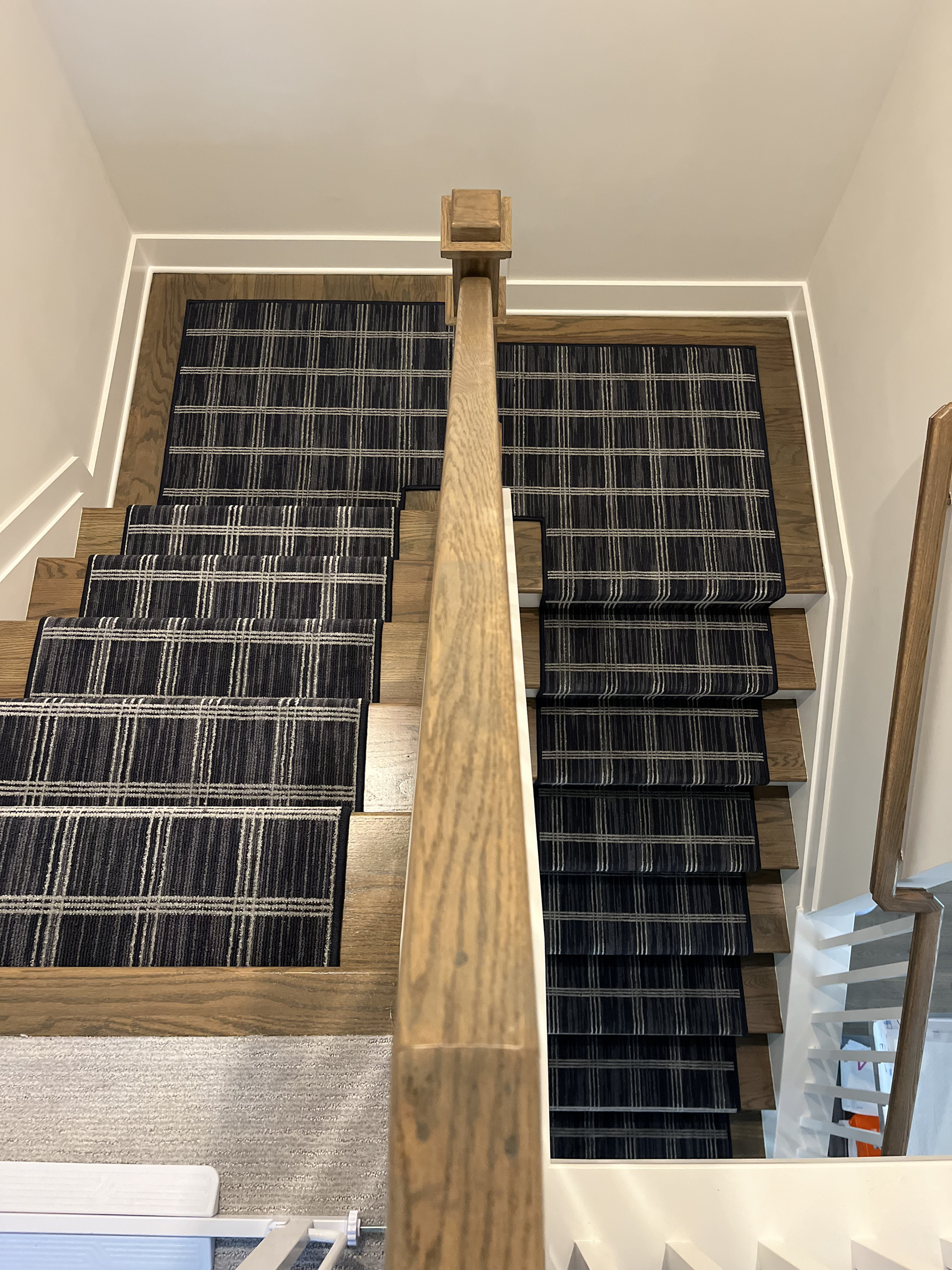 Carpeted staircase with a central wooden banister and black stair treads in a home interior