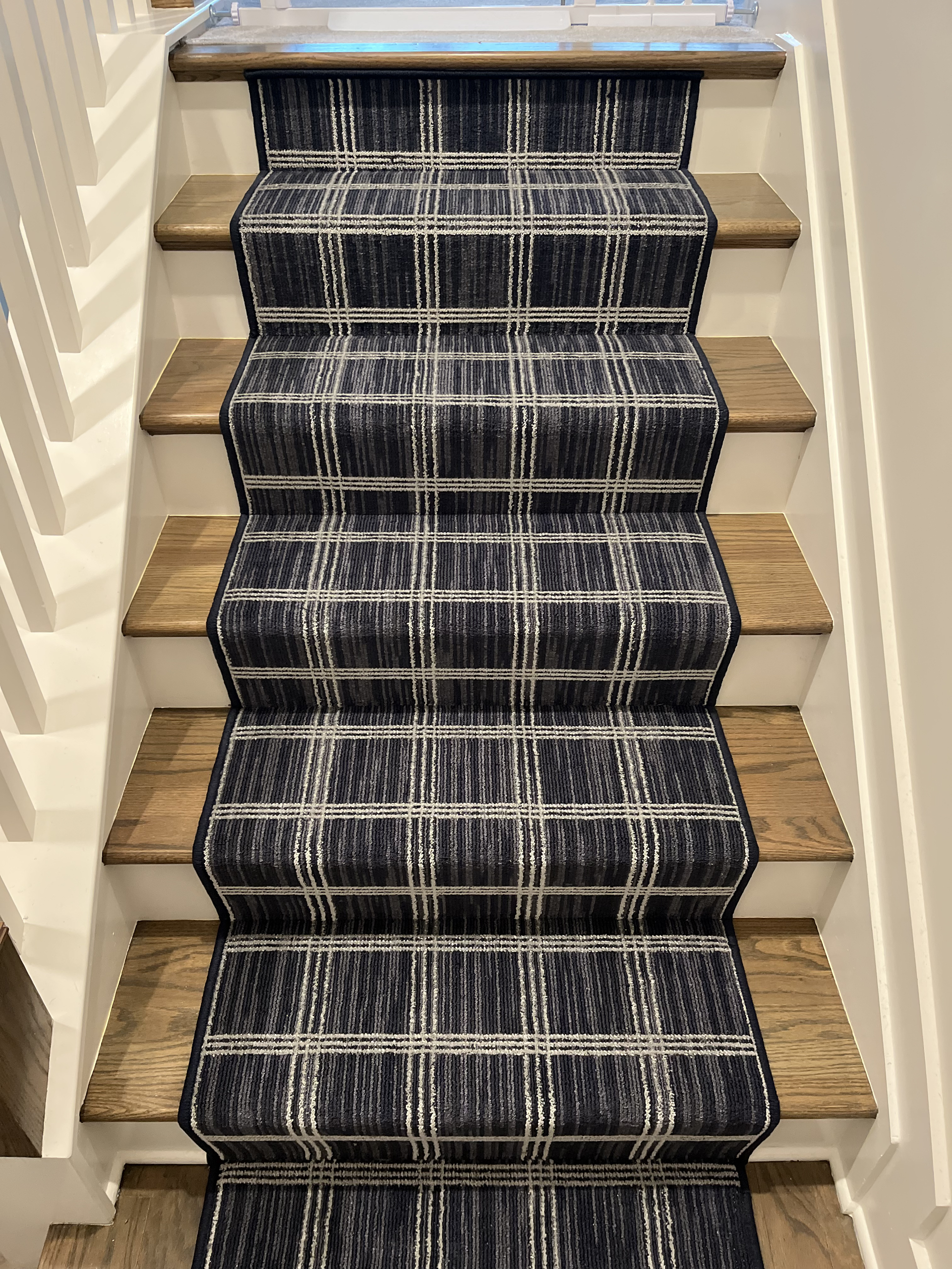 Carpeted staircase with a dark patterned runner and beige side walls.