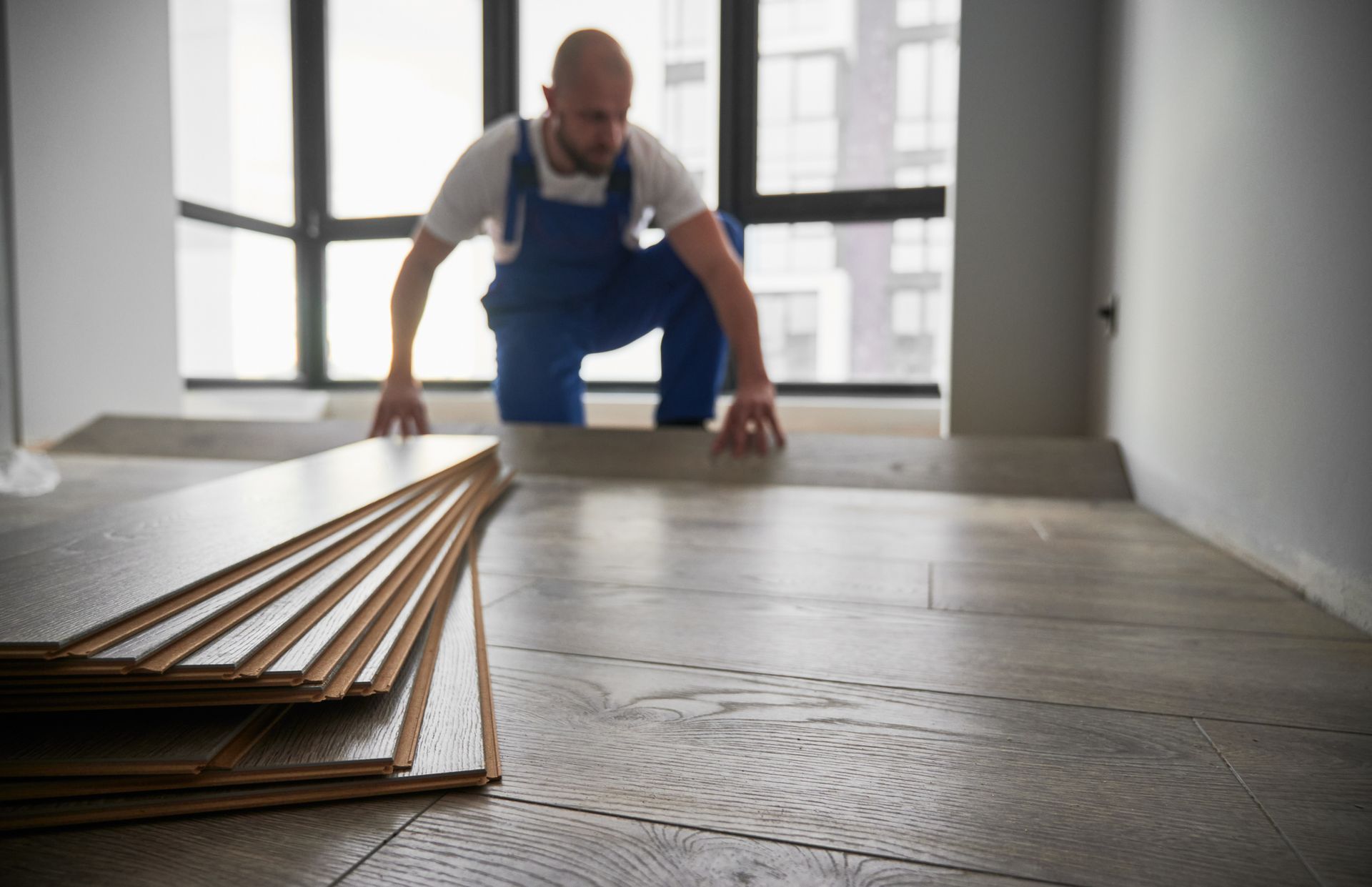 A man is installing a wooden floor in a room.