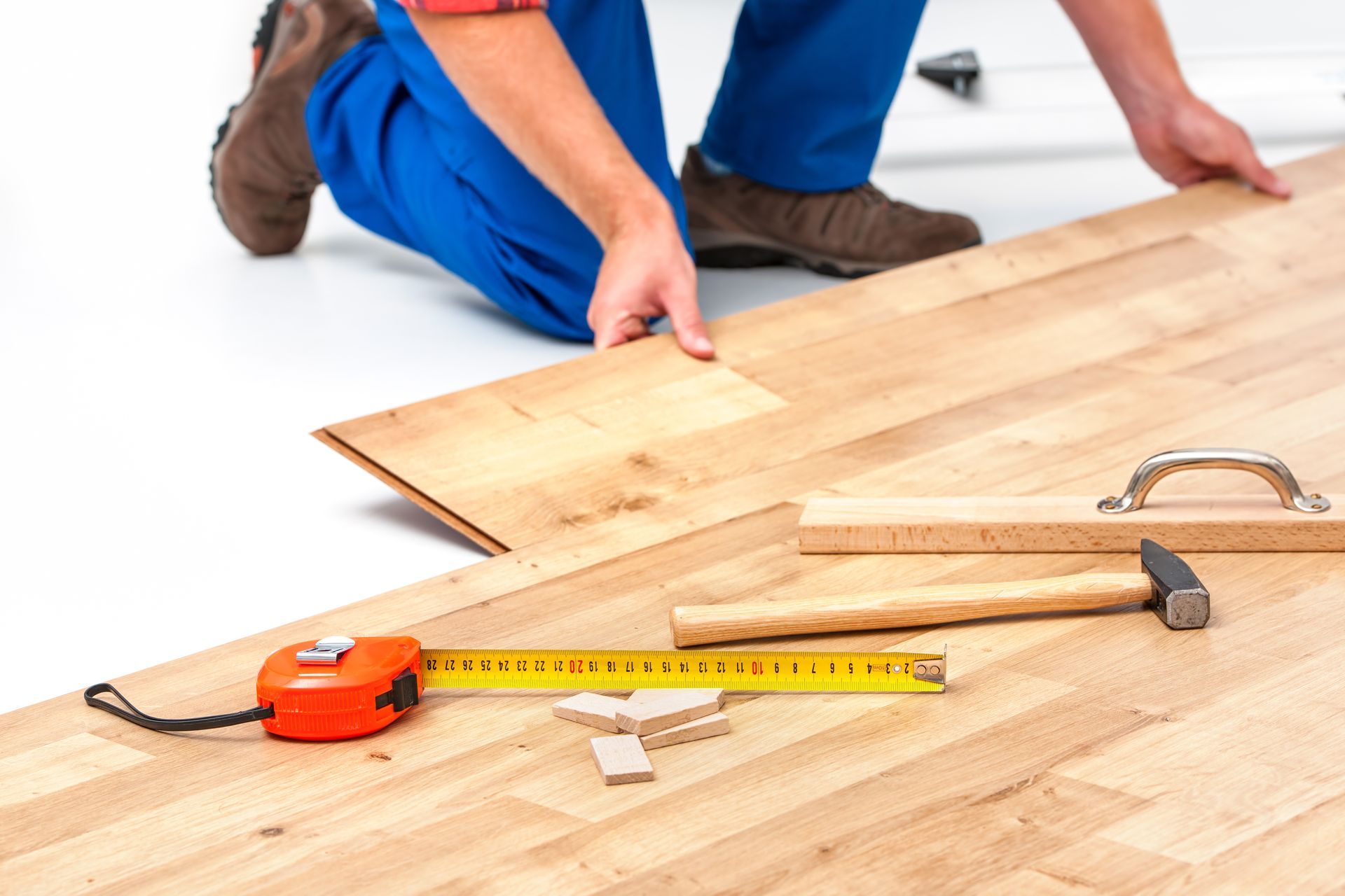 A man is measuring a piece of wood with a tape measure