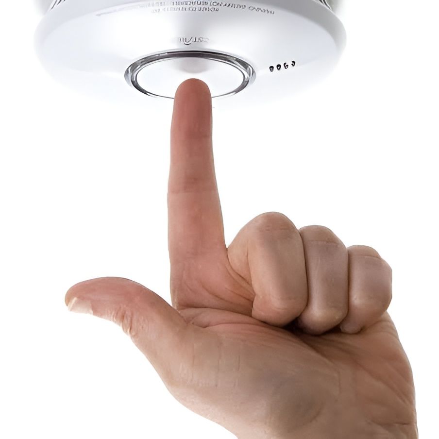 Hand Pressing the Test Button on a Smoke Detector