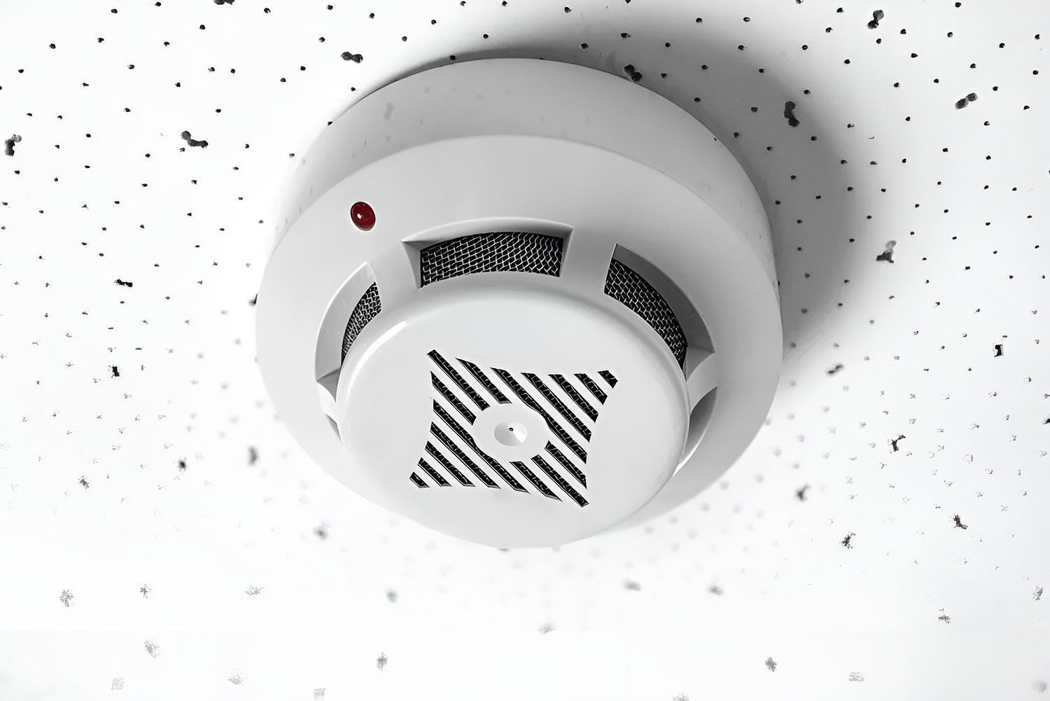 White Smoke Detector on a Textured White Ceiling