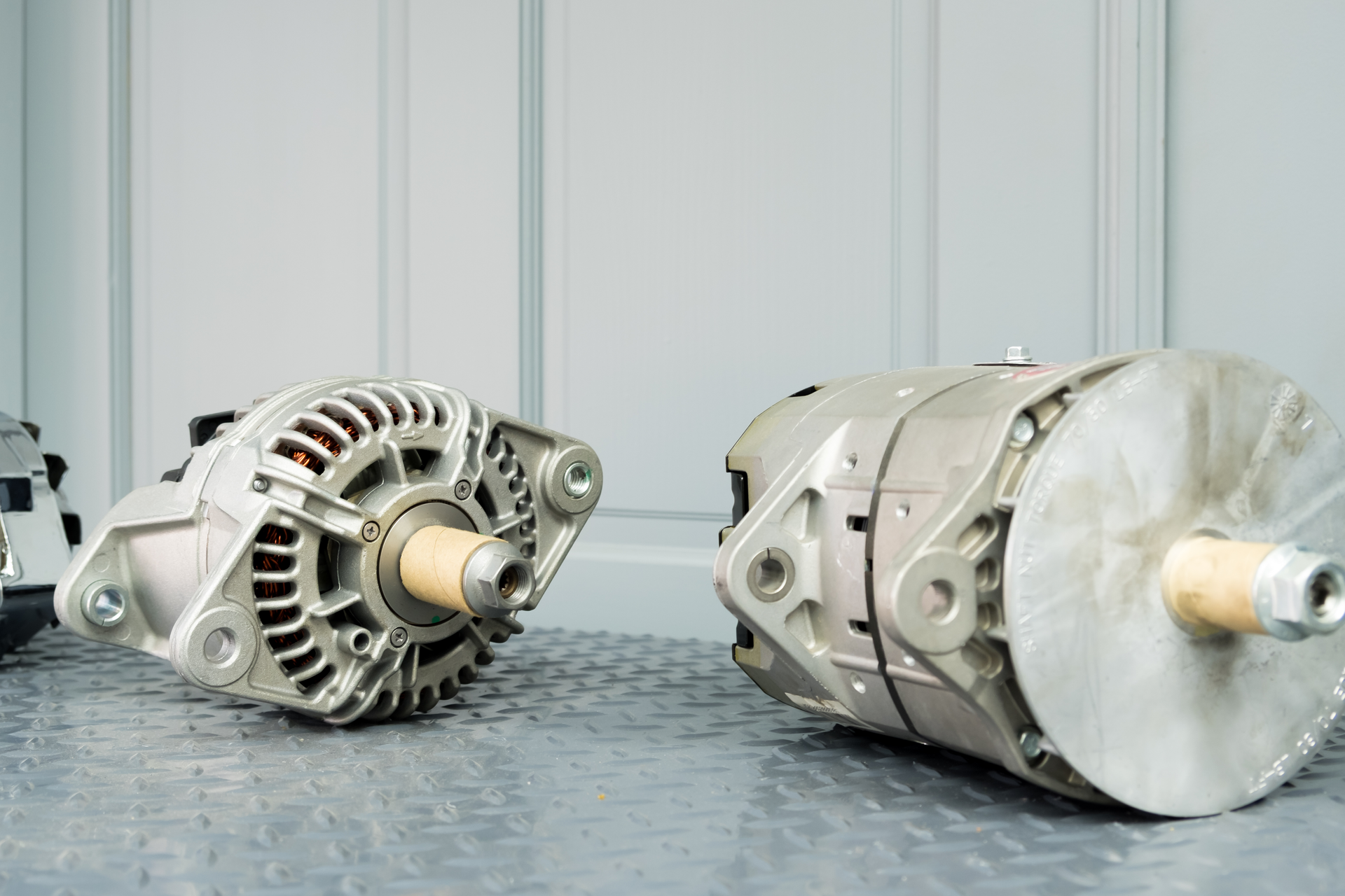 Two Car Alternators Showed On a Concrete Surface