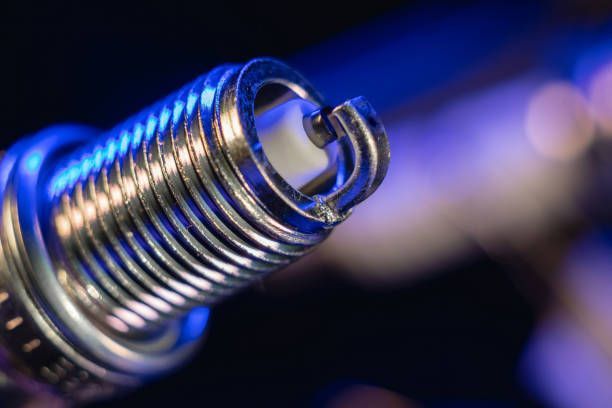 Close-up of a Standing Car Spark Plug Besides a Laid Spark Plug in a Dark Background
