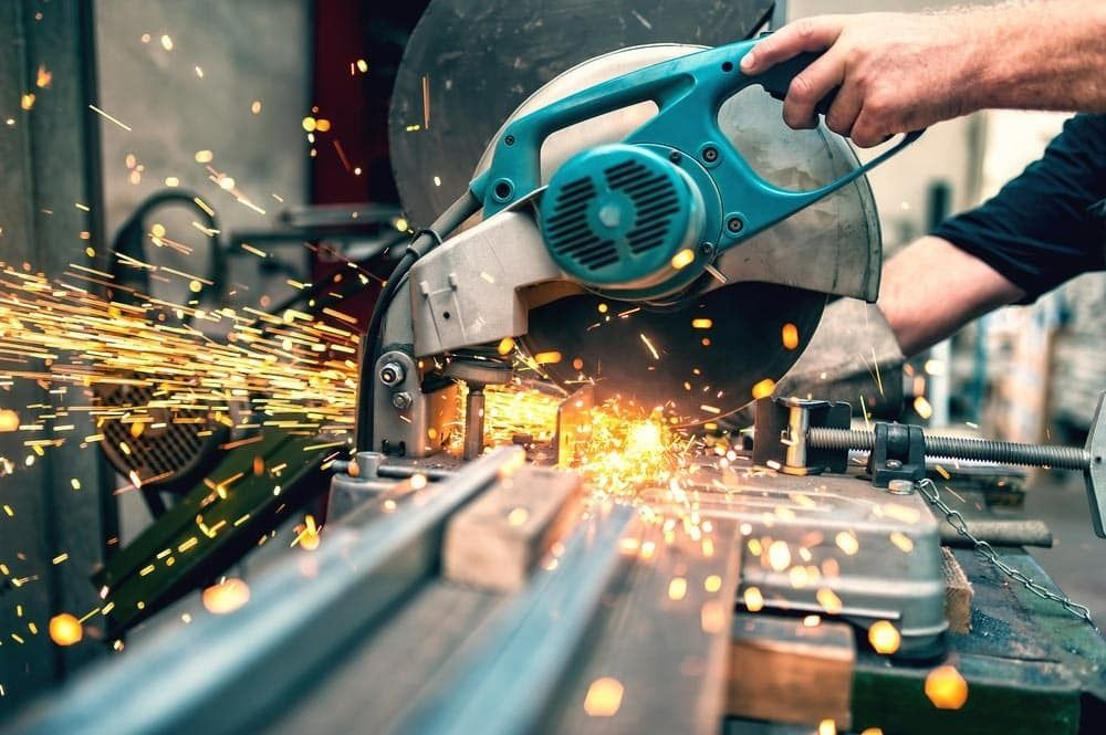 A Man is Cutting a Piece of Metal With a Circular Saw — Top End Steel Supplies Darwin In Pinelands, NT