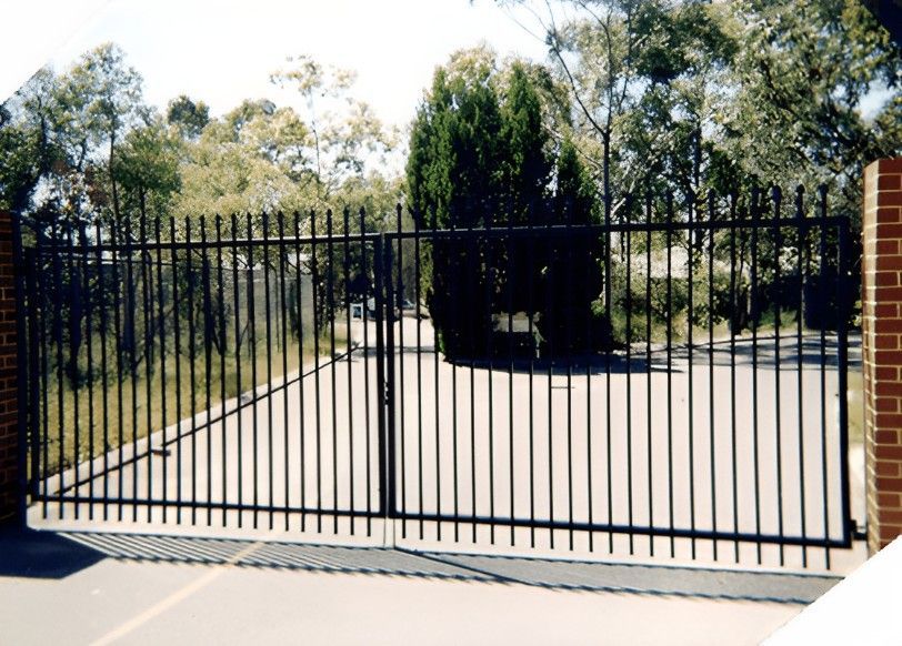 A Black Metal Gate is Open to a Driveway With Trees in the Background — Top End Steel Supplies Darwin In Pinelands, NT