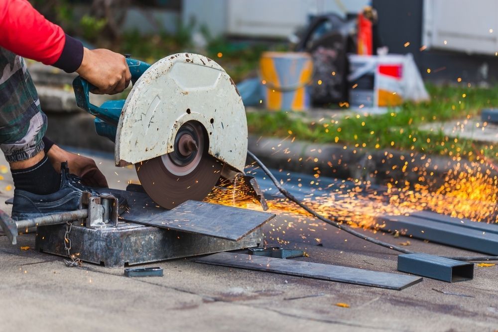 A Man is Cutting a Piece of Metal With a Circular Saw — Top End Steel Supplies Darwin In Pinelands, NT